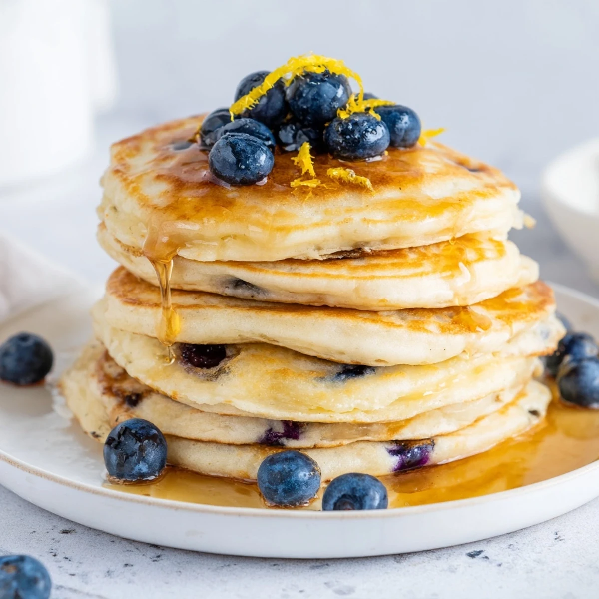 Golden Lemon Blueberry Pancakes stacked high, drizzled with warm maple syrup, ready for a sweet breakfast treat.