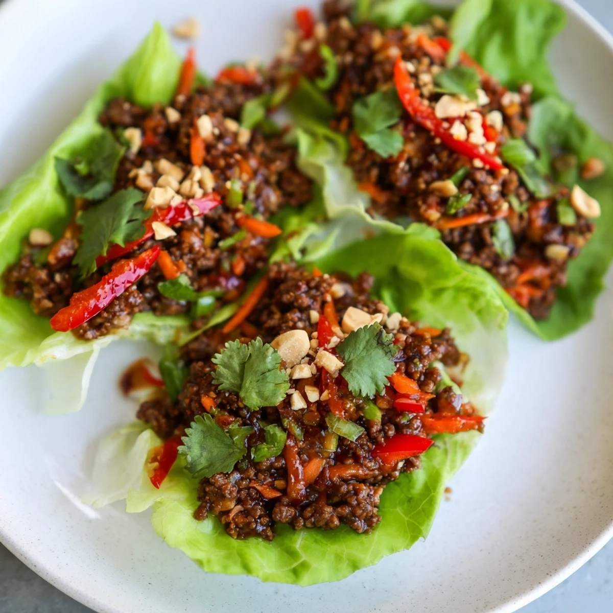 Crisp butter lettuce cups filled with savory ground beef, crunchy carrots, and red bell peppers, drizzled with tangy hoisin sauce for these Beef Lettuce Wraps.