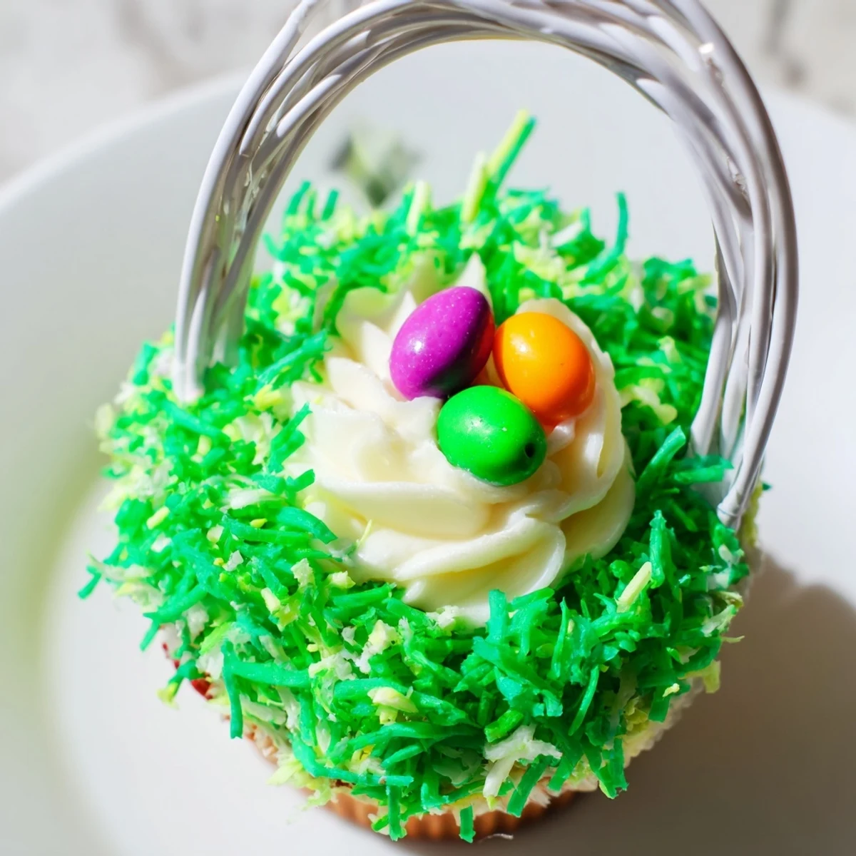 Enjoy these Easter Basket Cupcakes with a fluffy vanilla base, green coconut topping, and crunchy candy egg center.