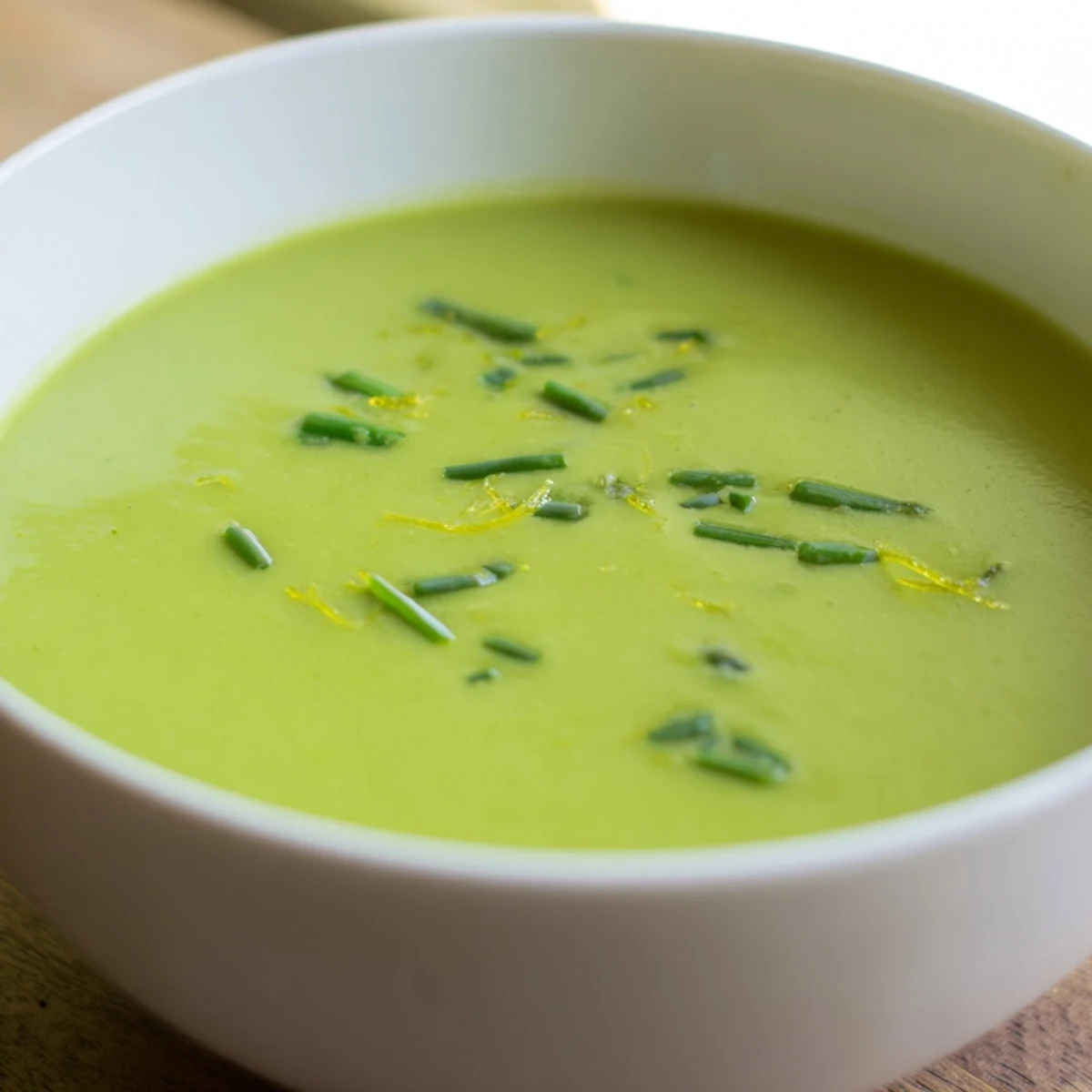 Creamy Asparagus Soup with Lemon served in a rustic bowl, garnished with fresh chives and a drizzle of olive oil.  