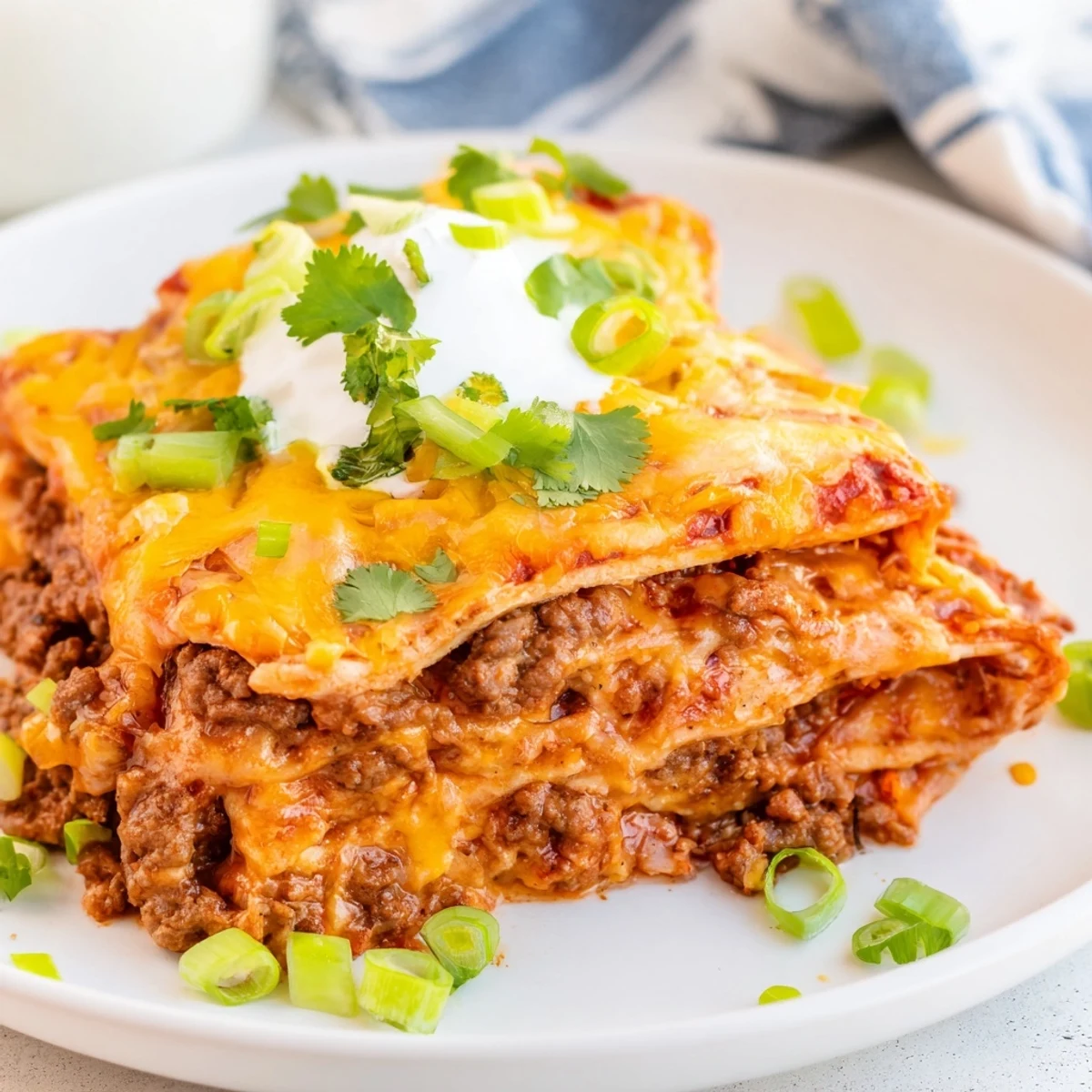 Steaming Beef Enchilada Casserole with Cheese features stacked corn tortillas and ground beef in a savory red enchilada sauce.
