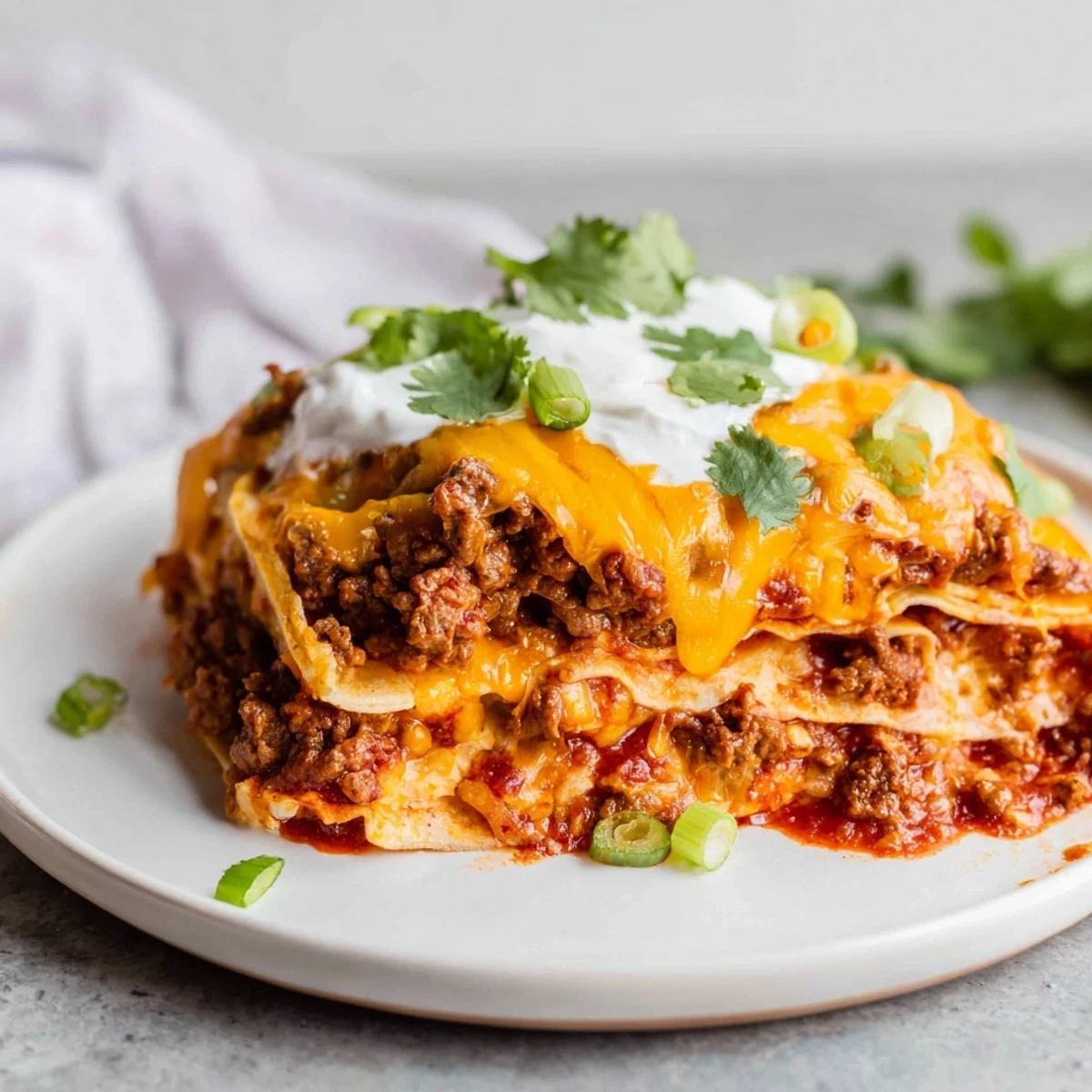 Hearty Beef Enchilada Casserole with Cheddar in a baking dish, garnished with cilantro and green onions for a family meal.