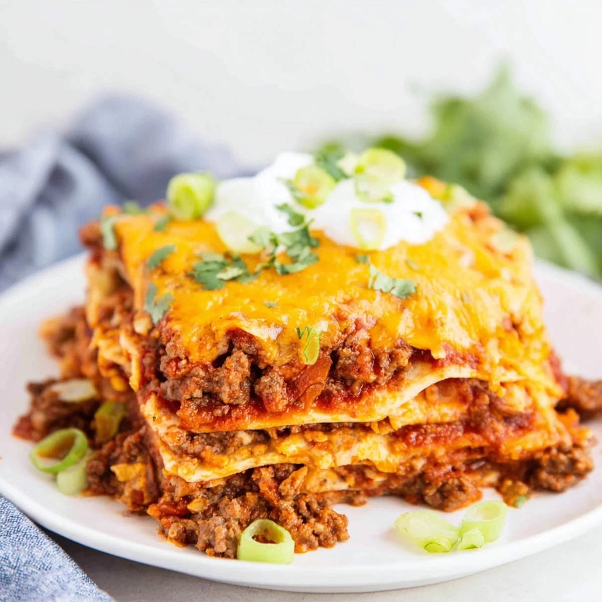 Golden-brown melted cheddar and Monterey Jack cheese bubble atop layers of seasoned ground beef and corn tortillas in this Beef Enchilada Casserole, garnished with fresh cilantro and green onions.