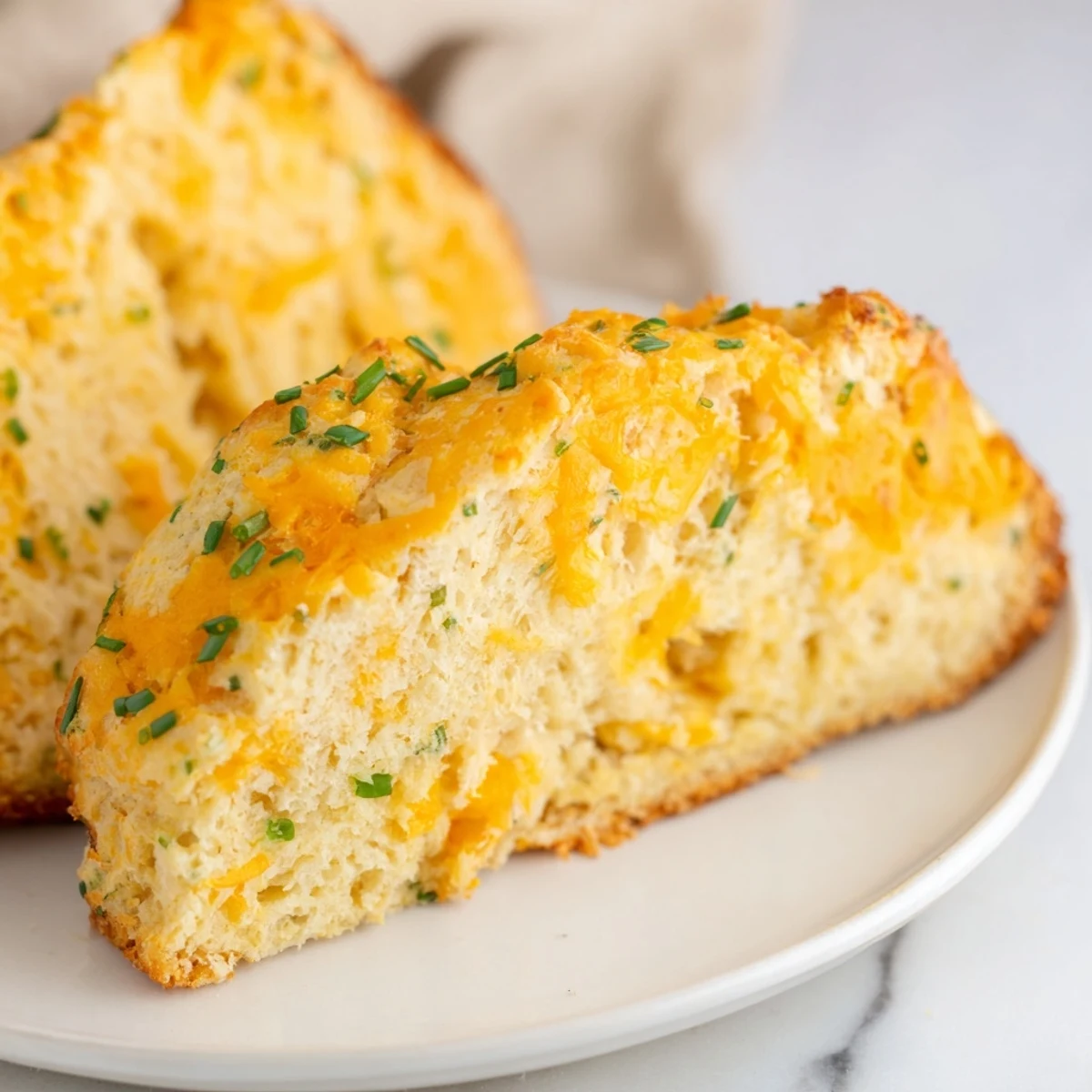 Warm Savory Cheddar & Chive Irish Soda bread served beside steaming soup for a cozy meal.