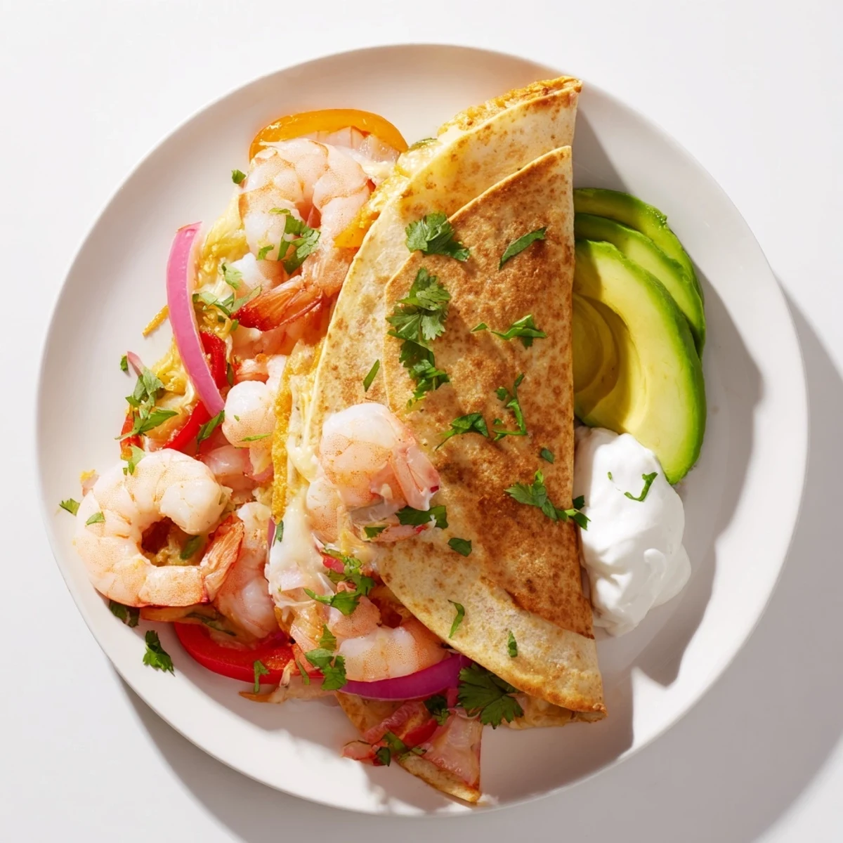 A close-up of Shrimp Fajita Sheet Pan Quesadillas with melted Mexican cheese and a side of fresh salsa and avocado.
