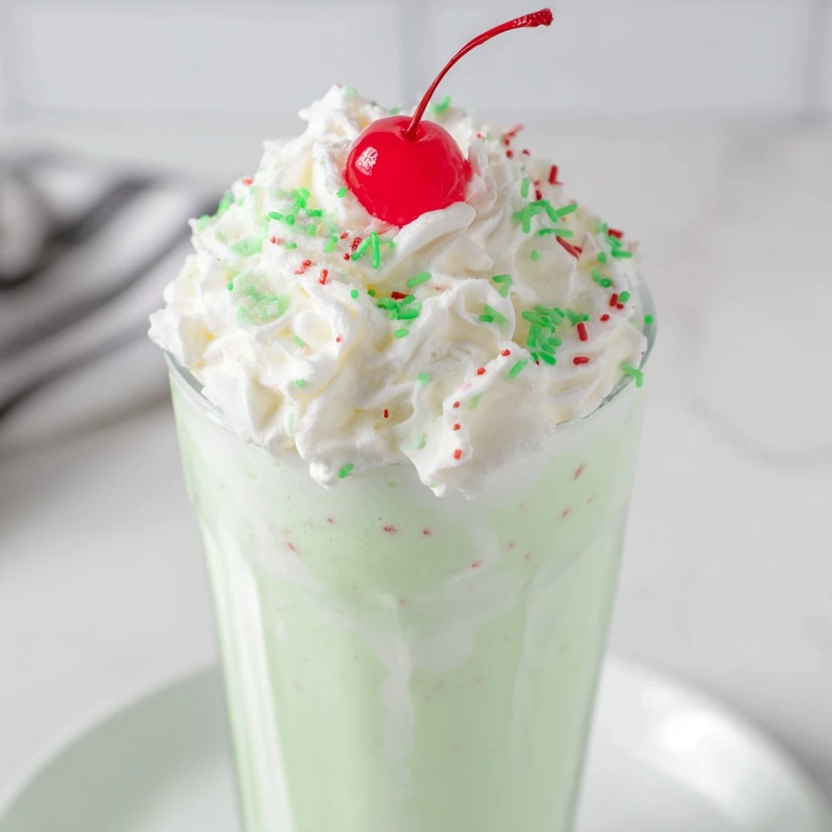 Close-up of a creamy Homemade Copycat Shamrock Shake showing minty texture and a cherry garnish.