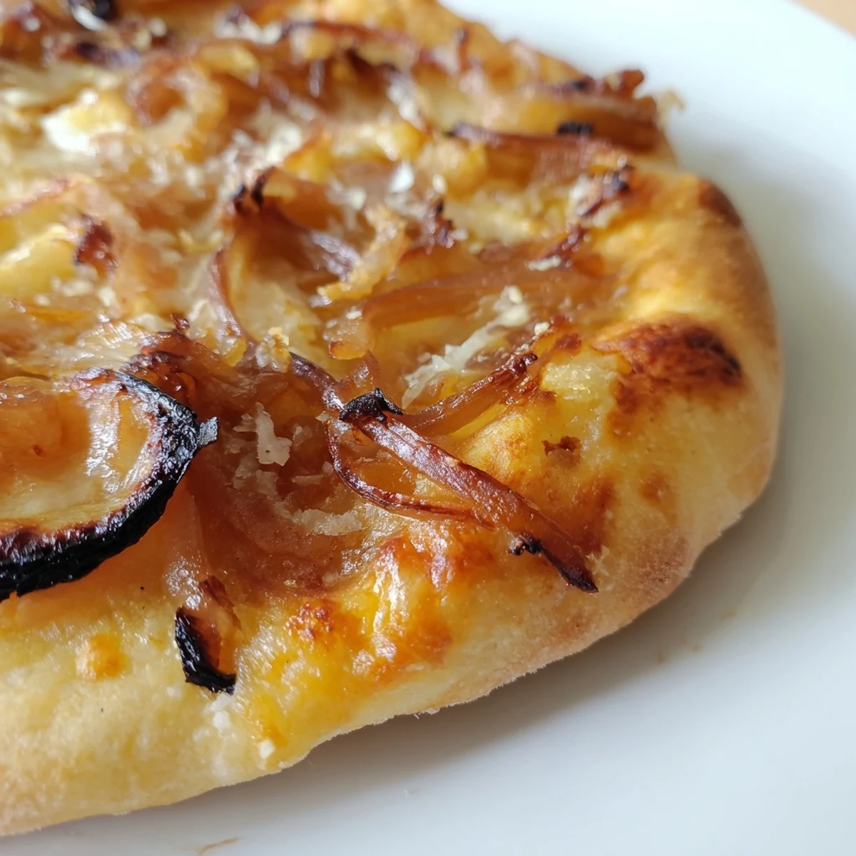 The caramelized onion pizza showcases a golden-brown, crispy crust topped with sweet onions and gooey melted cheeses, served on a wooden board.