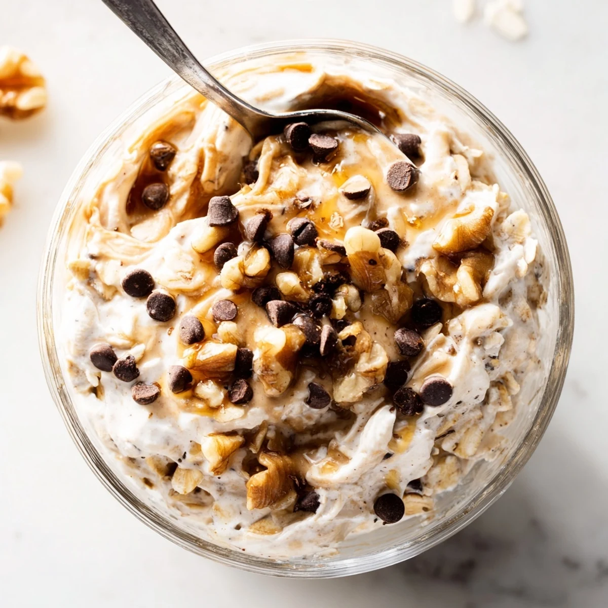 Cookie Dough Overnight Oats layered with Greek yogurt and oats, topped with walnuts and a drizzle of nut butter.