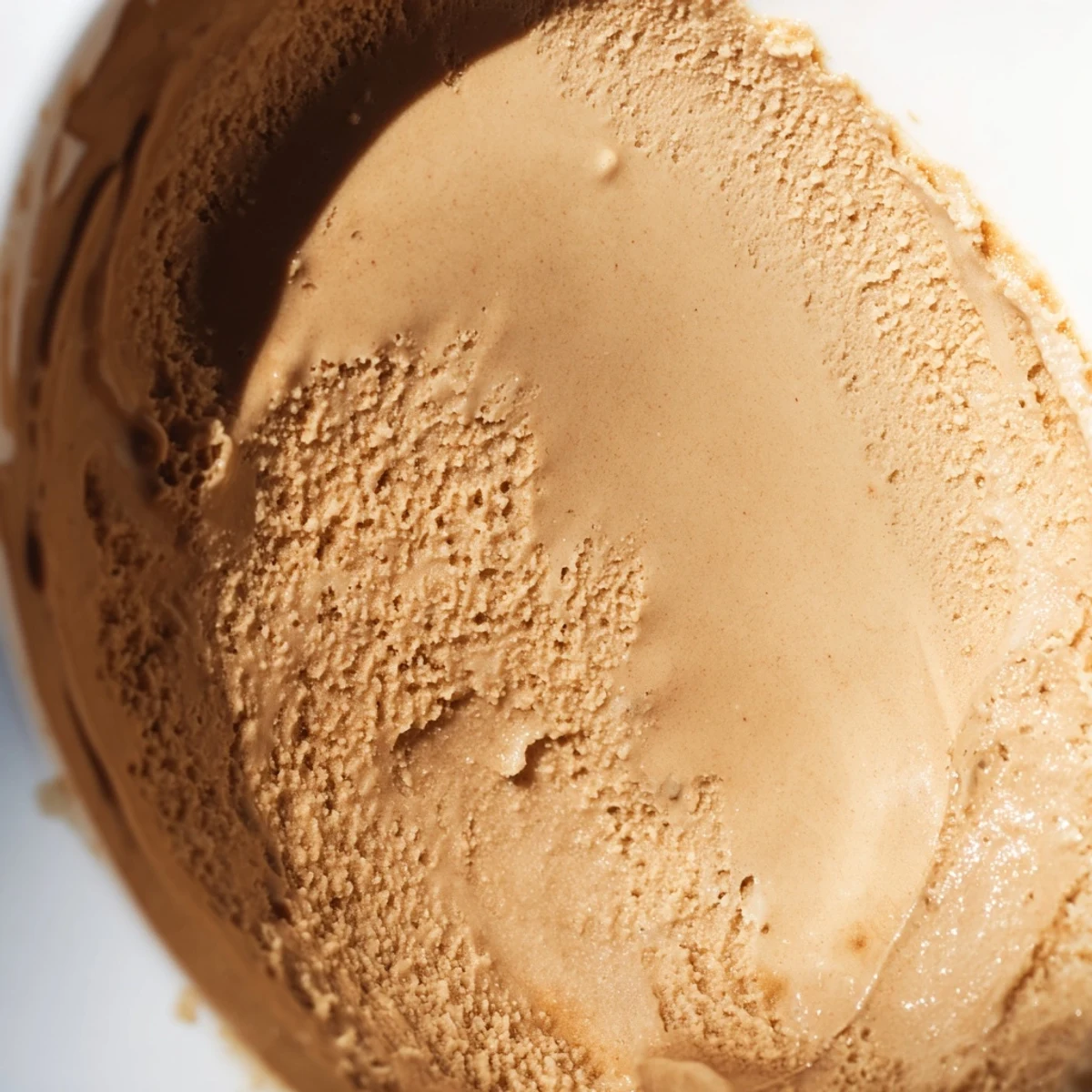 Creamy Hojicha Ice Cream scoops into a rustic bowl, topped with toasted sesame seeds and a drizzle of black sugar syrup for serving.