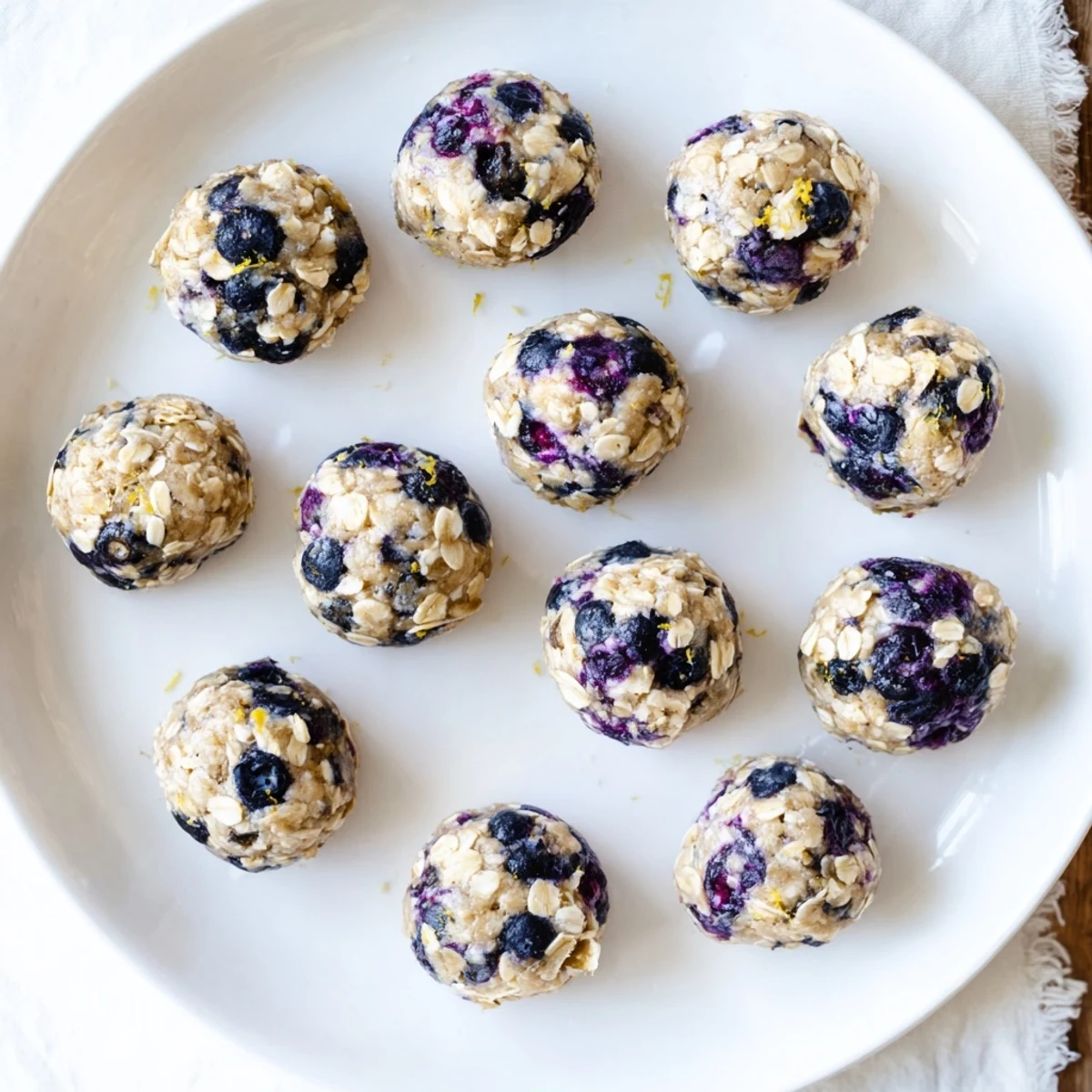 A close-up of Blueberry Cheesecake Protein Bites, highlighting blueberry specks and a creamy coating.