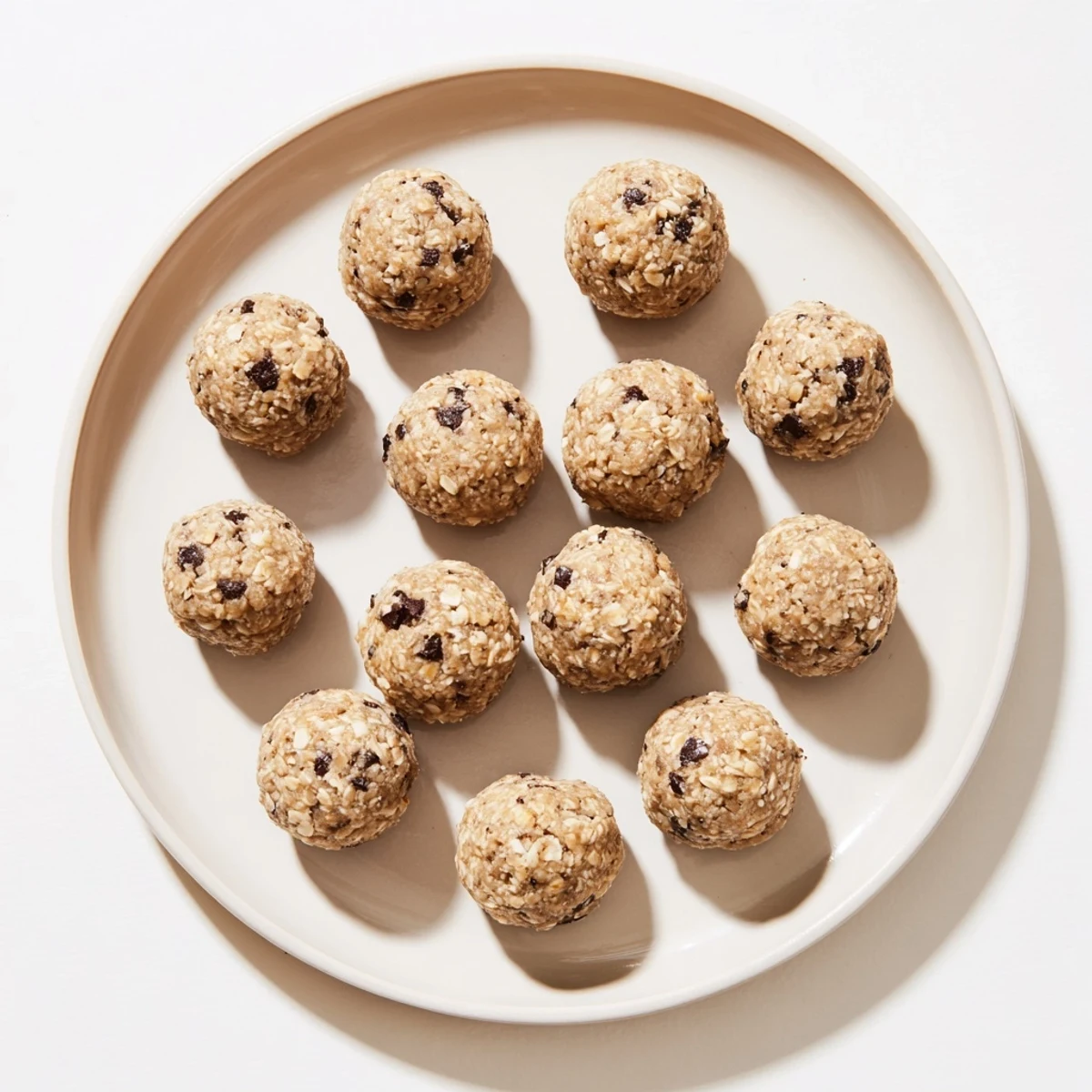 A hand holding a single mint chocolate chip protein ball, highlighting chewy oats and melty chocolate chips.  