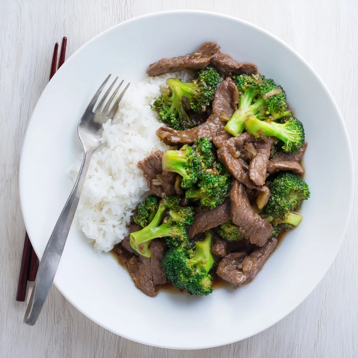 A close-up shows Better Than Takeout Beef With Broccoli sizzling in a wok, garnished with sesame seeds.