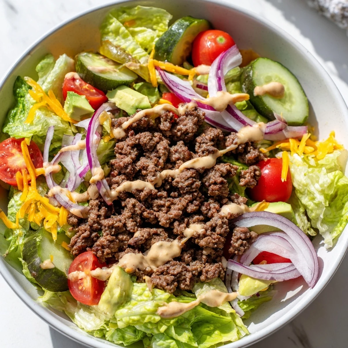 Gluten-free burger bowls layered with romaine, spiced ground beef, avocado, and homemade sauce