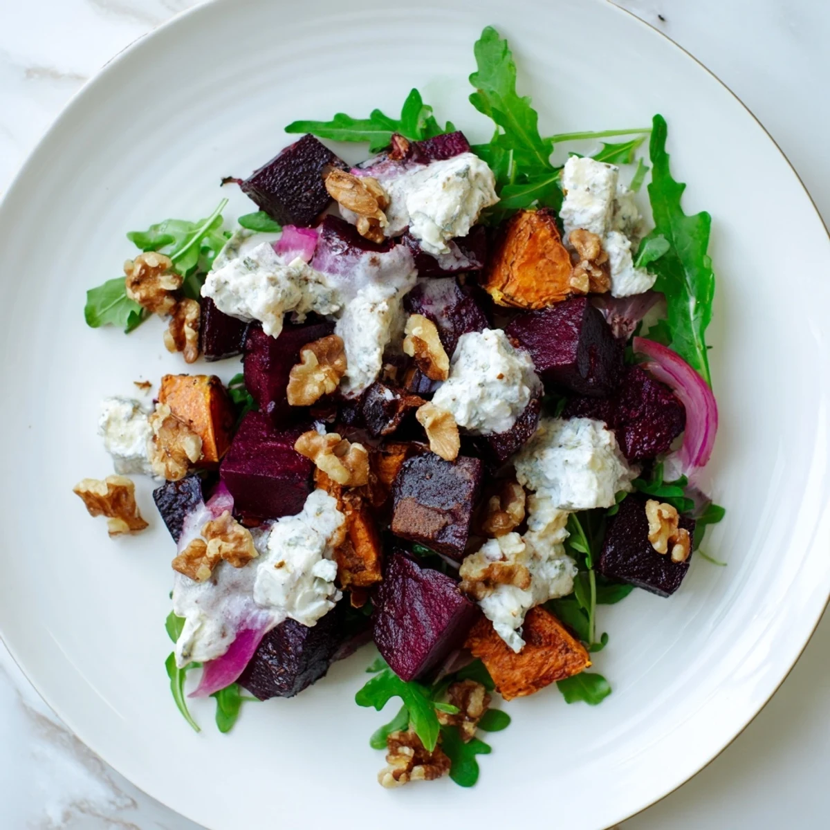 Colorful creamy roasted beet salad featuring sweet potatoes, walnuts, and tangy feta cheese drizzled with luscious yogurt dressing
