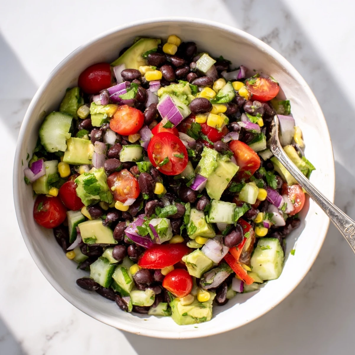 Fresh black bean salad featuring diced red peppers, corn, cucumber, and vibrant cilantro garnish