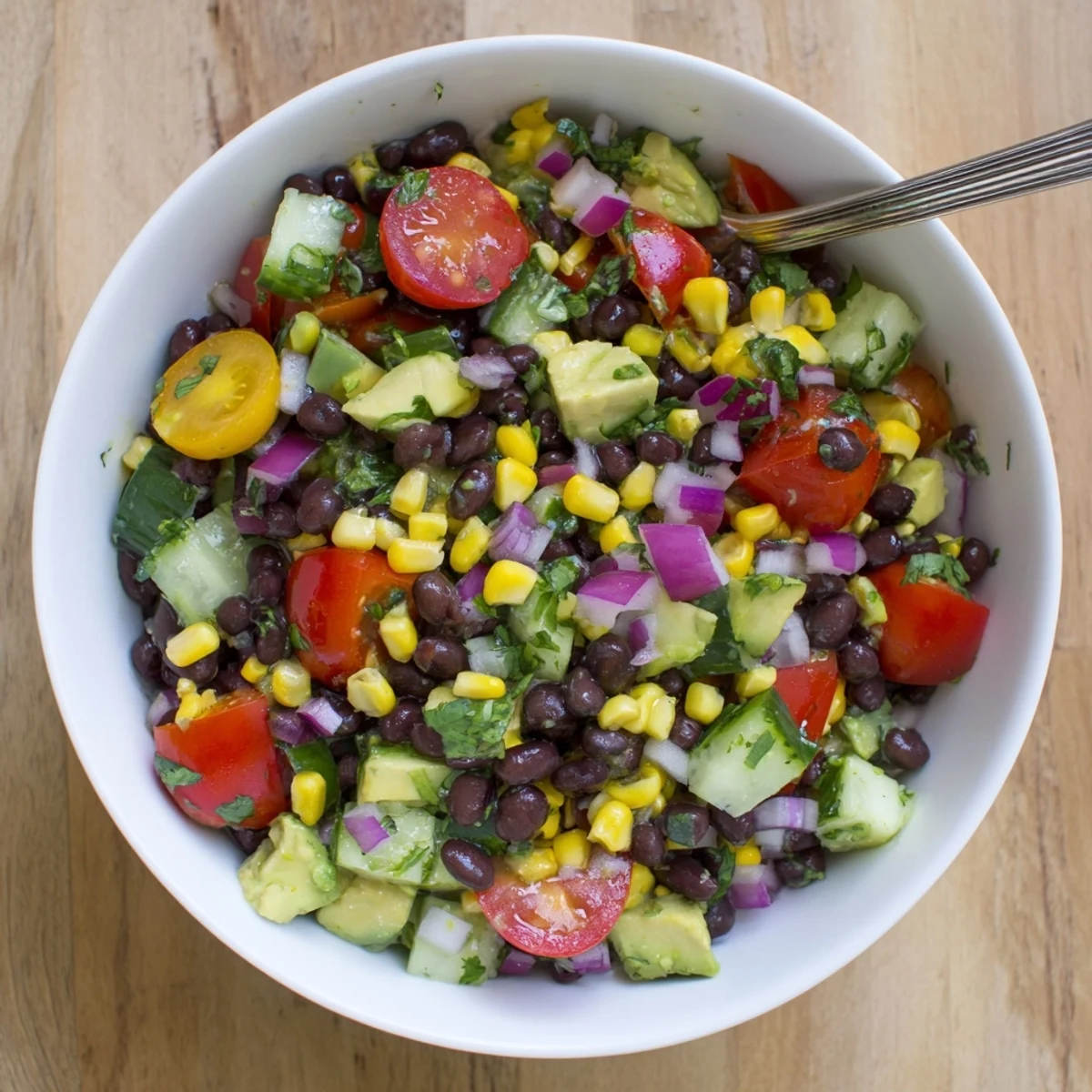 Colorful chopped black bean salad bowl with crisp vegetables, creamy avocado, and zesty lime dressing