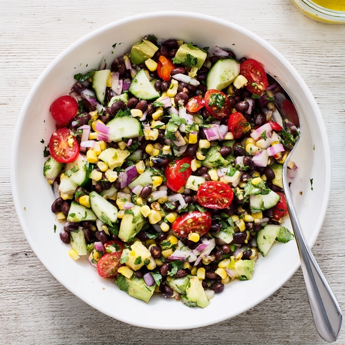 Protein-packed chopped black bean salad with ripe avocado chunks, cherry tomatoes, and tangy dressing