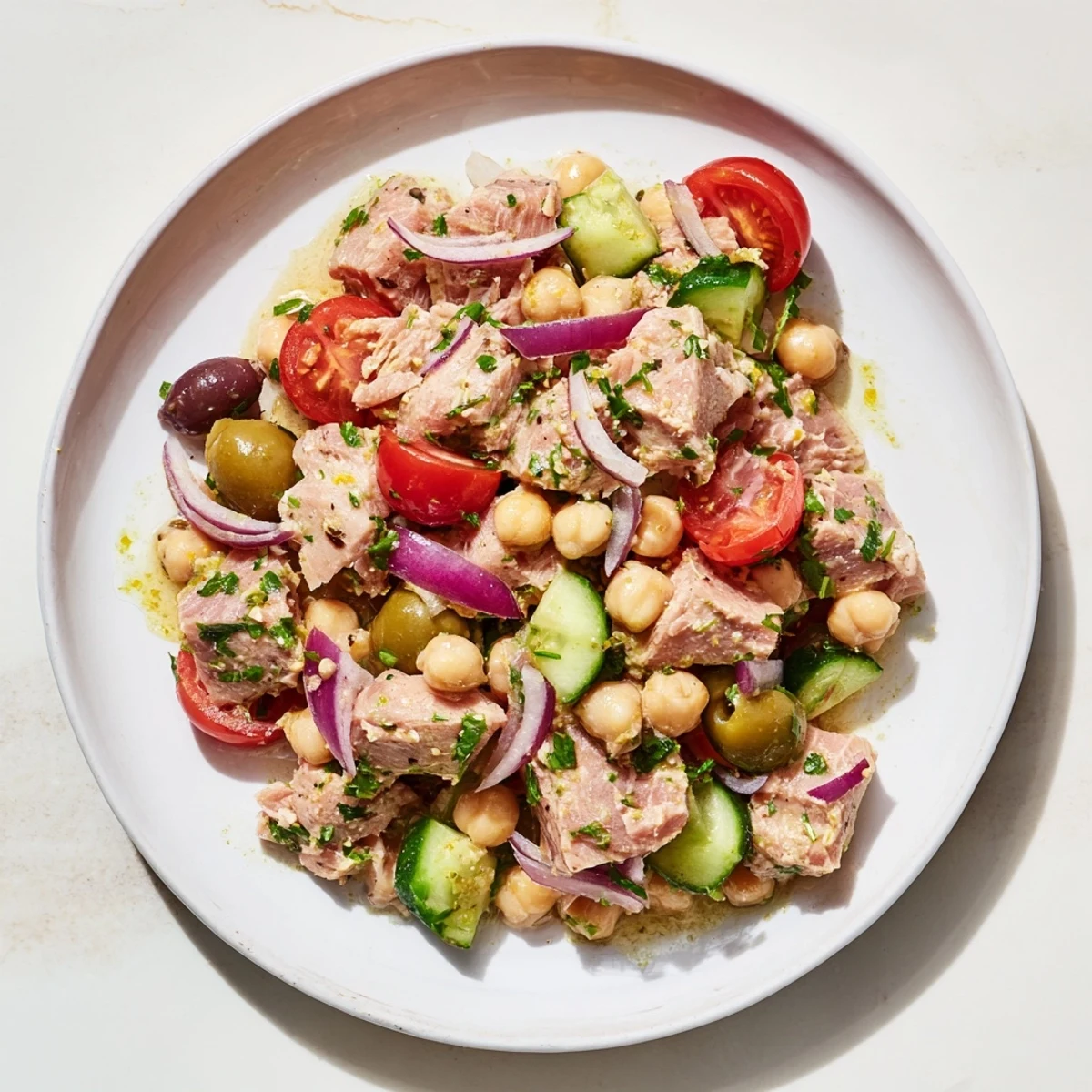 Colorful hearty tuna and garbanzo bean salad with fresh vegetables and zesty lemon dressing in a white bowl