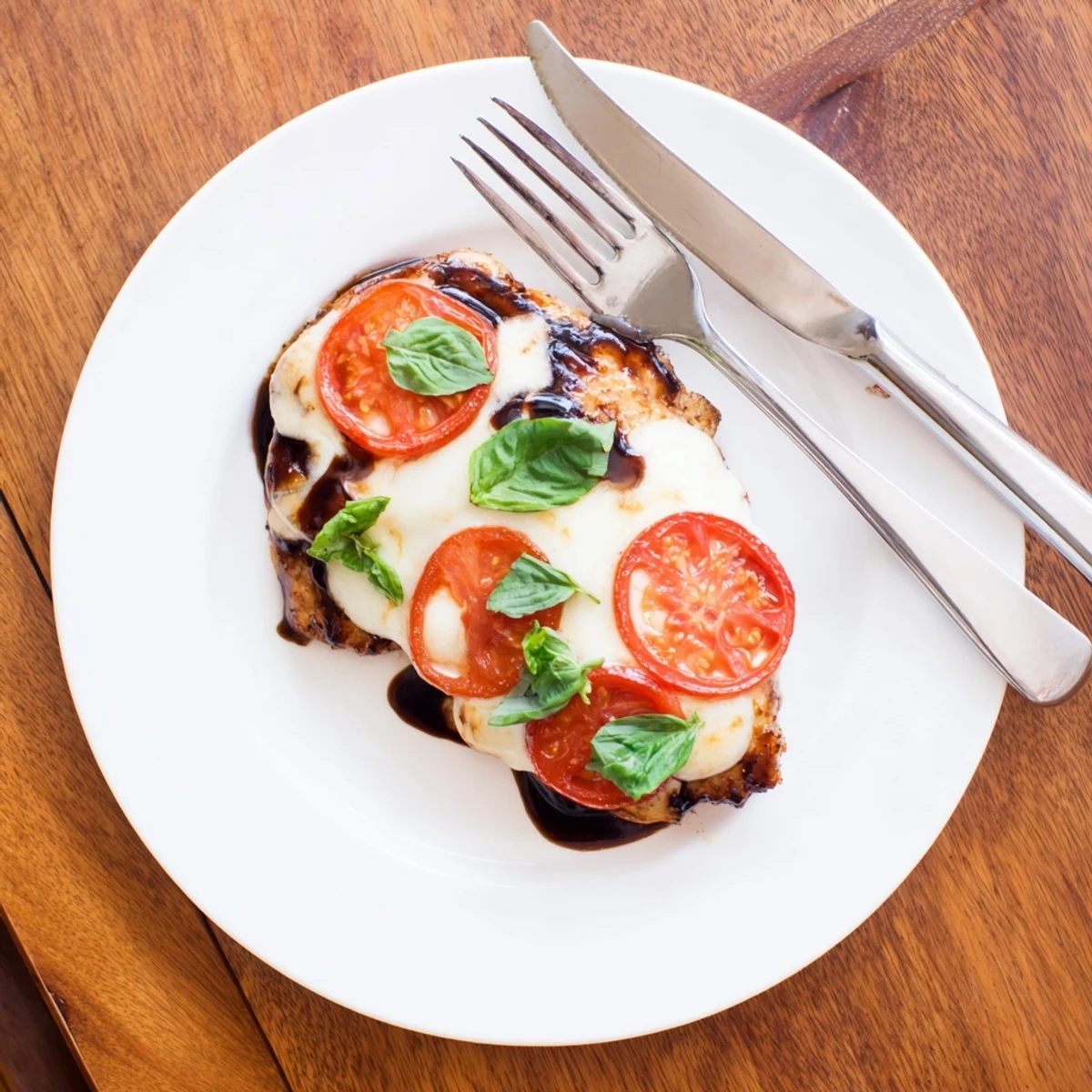 Golden brown chicken breasts topped with melted mozzarella and fresh basil leaves