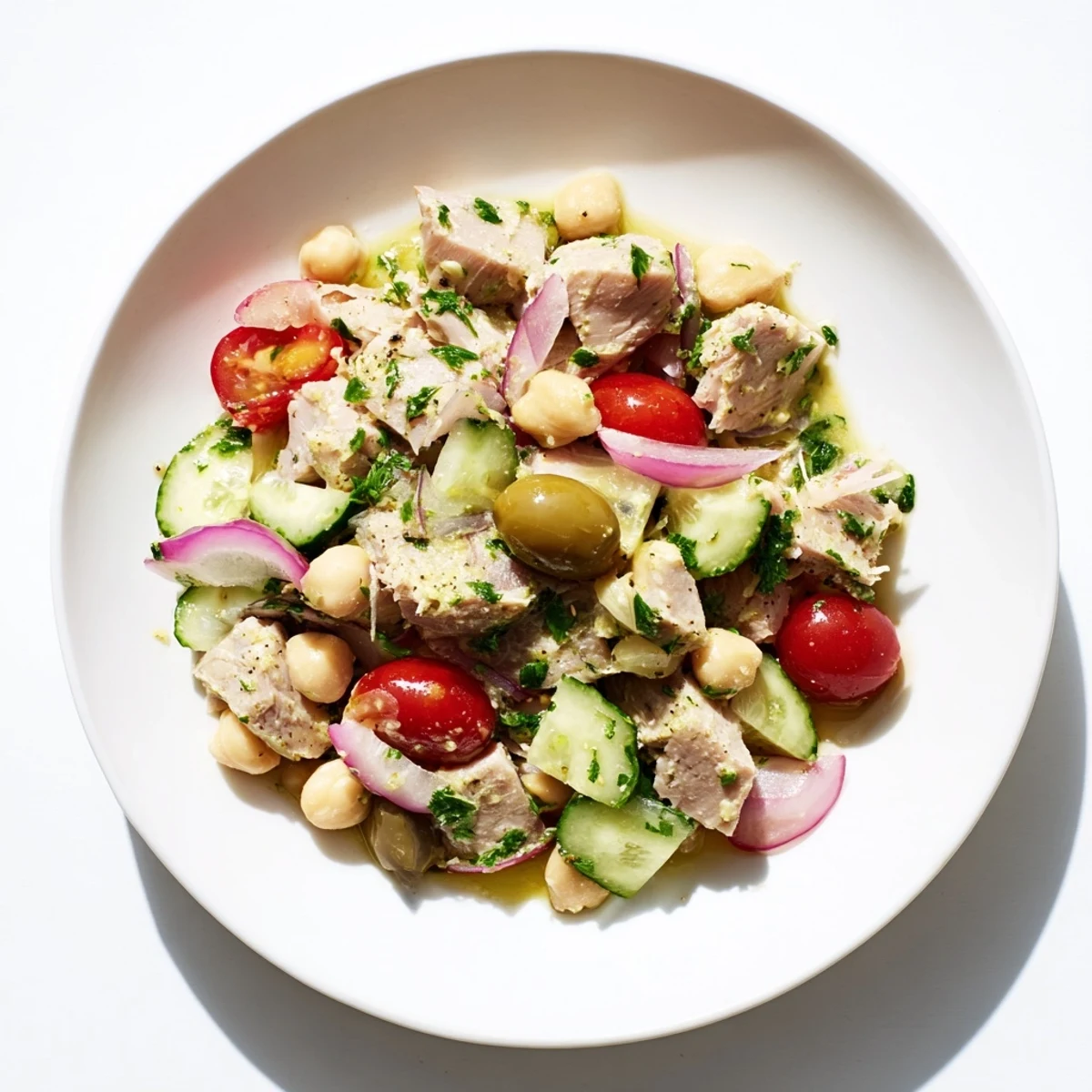 Mediterranean-style tuna and garbanzo bean salad plated with crisp cucumber tomatoes and aromatic herbs