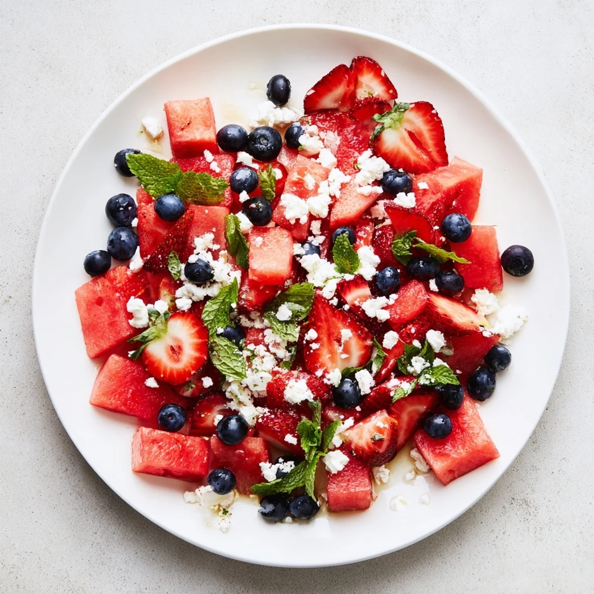 Colorful strawberry watermelon salad with honey lime vinaigrette topped with fresh mint leaves
