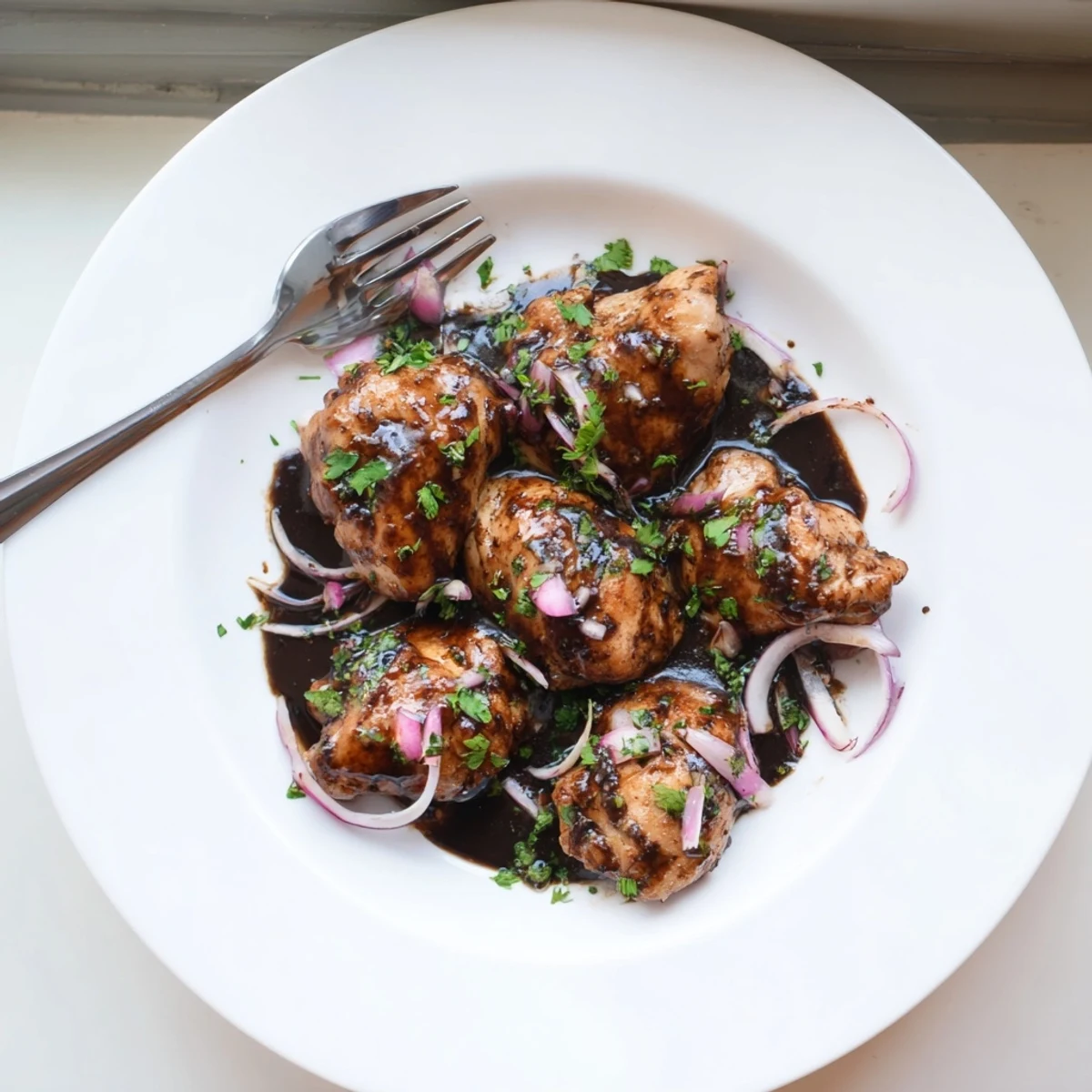 Tender chicken pieces simmering in sweet balsamic glaze with caramelized red onion pieces