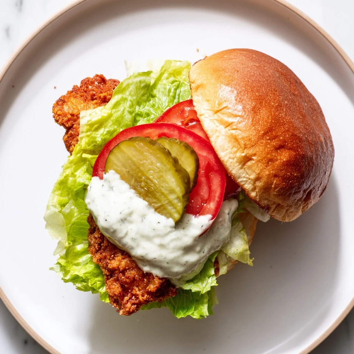 Spicy fried chicken breast topped with creamy garlic aioli and fresh pickles on bun