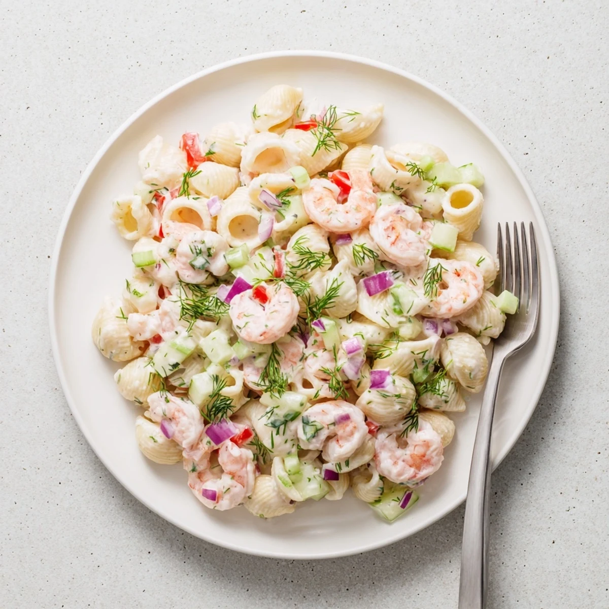 Creamy shrimp pasta salad featuring tender pink shrimp, colorful diced vegetables, and tangy dressing in a white serving bowl