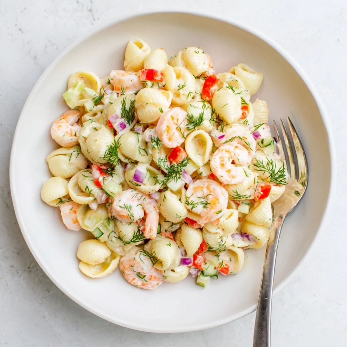 Close-up of creamy shrimp pasta salad with al dente pasta shells, fresh herbs, and coated in a zesty white dressing