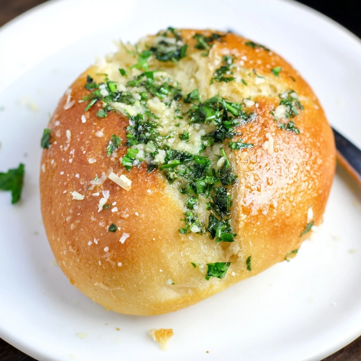 Soft warm garlic bread rolls brushed with parsley and Parmesan on a serving platter