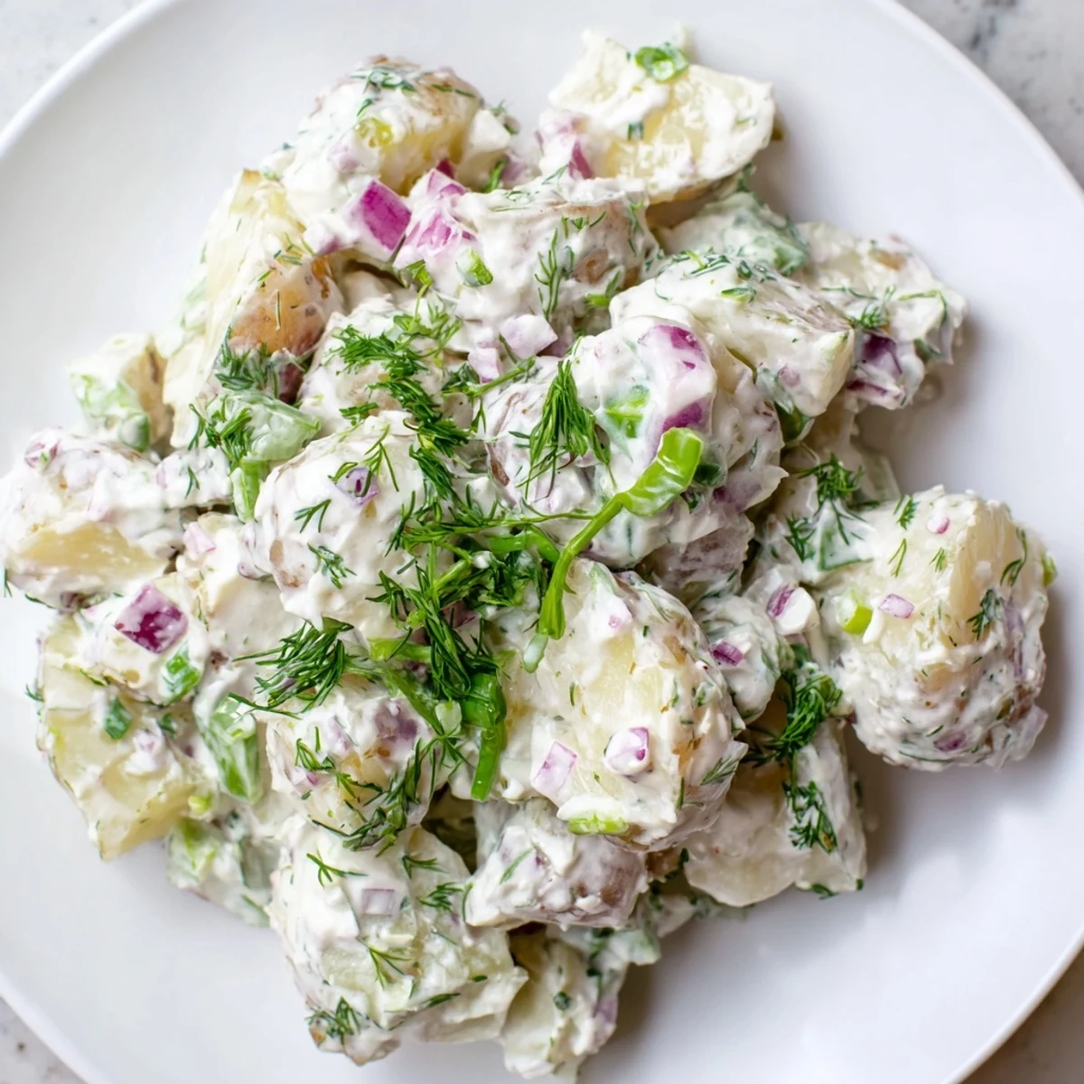 Light and tangy Greek yogurt potato salad tossed with diced red onion, fragrant dill, and parsley for summer picnics