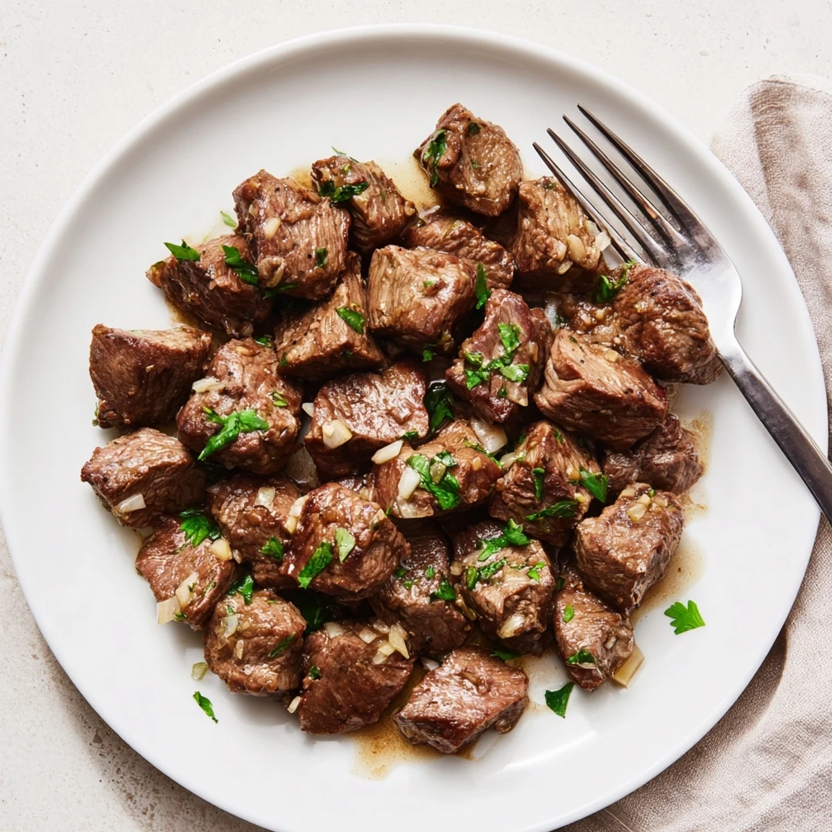Golden brown crockpot steak bites coated in garlic butter herb sauce and garnished with fresh parsley