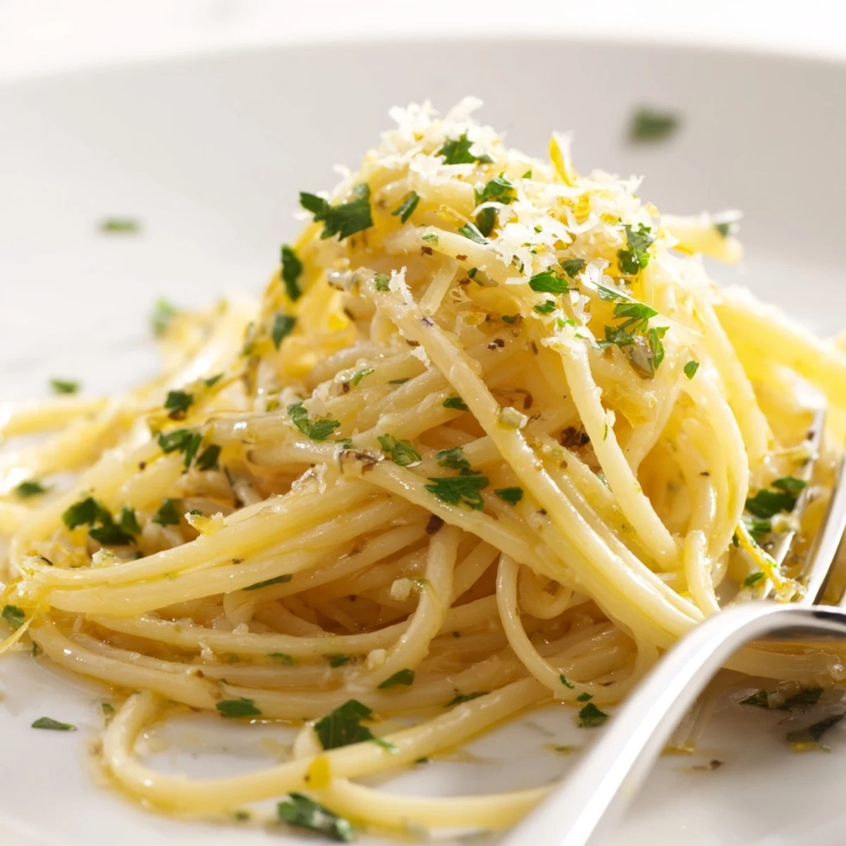 Twirled spaghetti swimming in rich garlic butter sauce finished with lemon zest and grated cheese