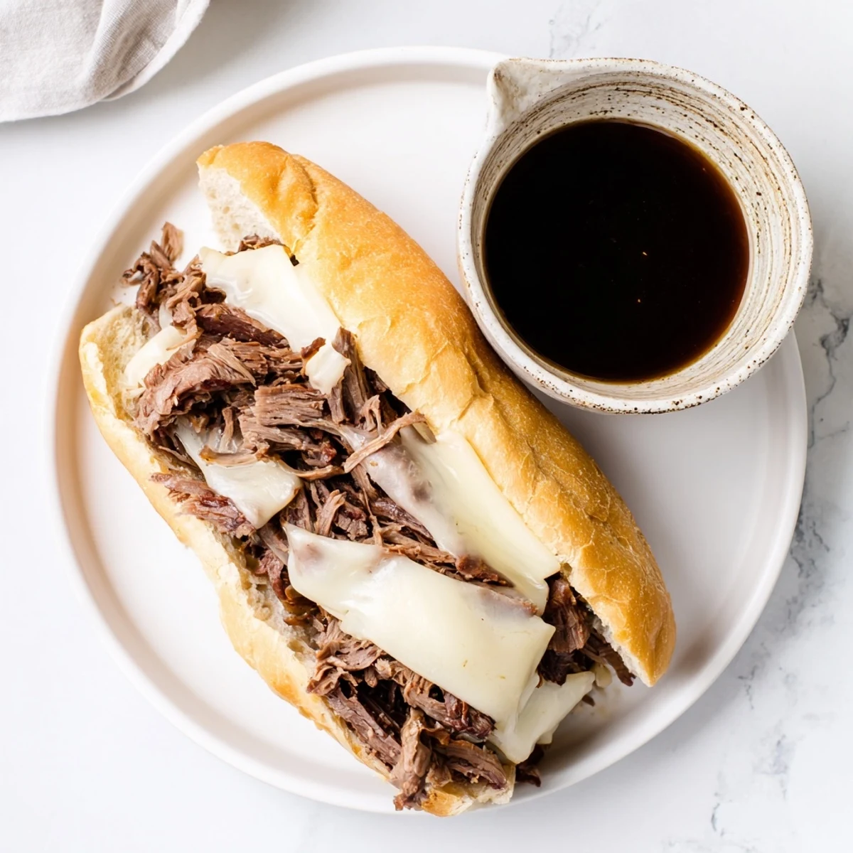 Slow cooker French Dip Sandwiches plated alongside small ramekins of rich, savory au jus dipping sauce