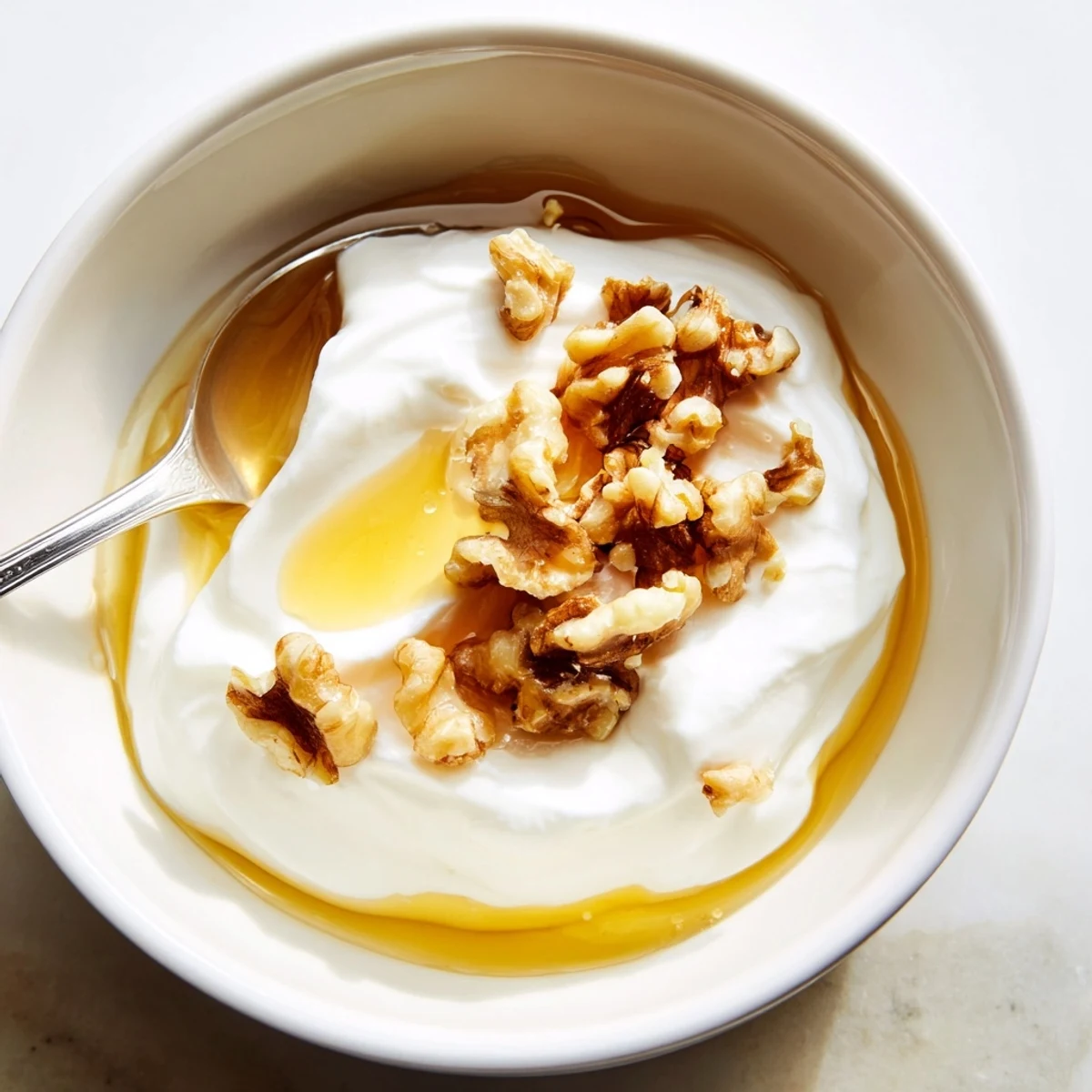 Thick strained Greek yogurt spoon displaying rich texture on a wooden spoon with honey