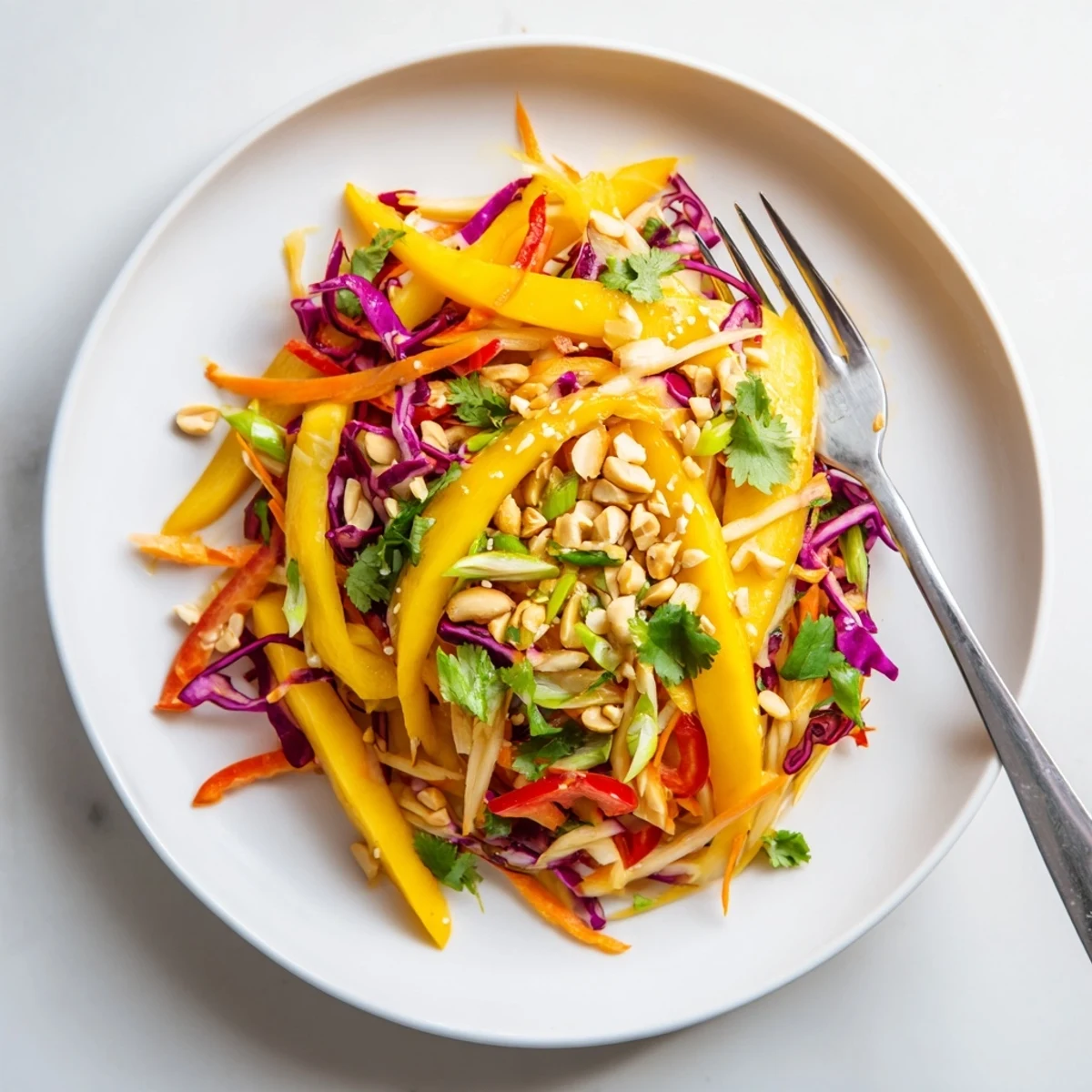 Vibrant refreshing mango slaw topped with toasted sesame seeds and fresh cilantro on a white serving plate