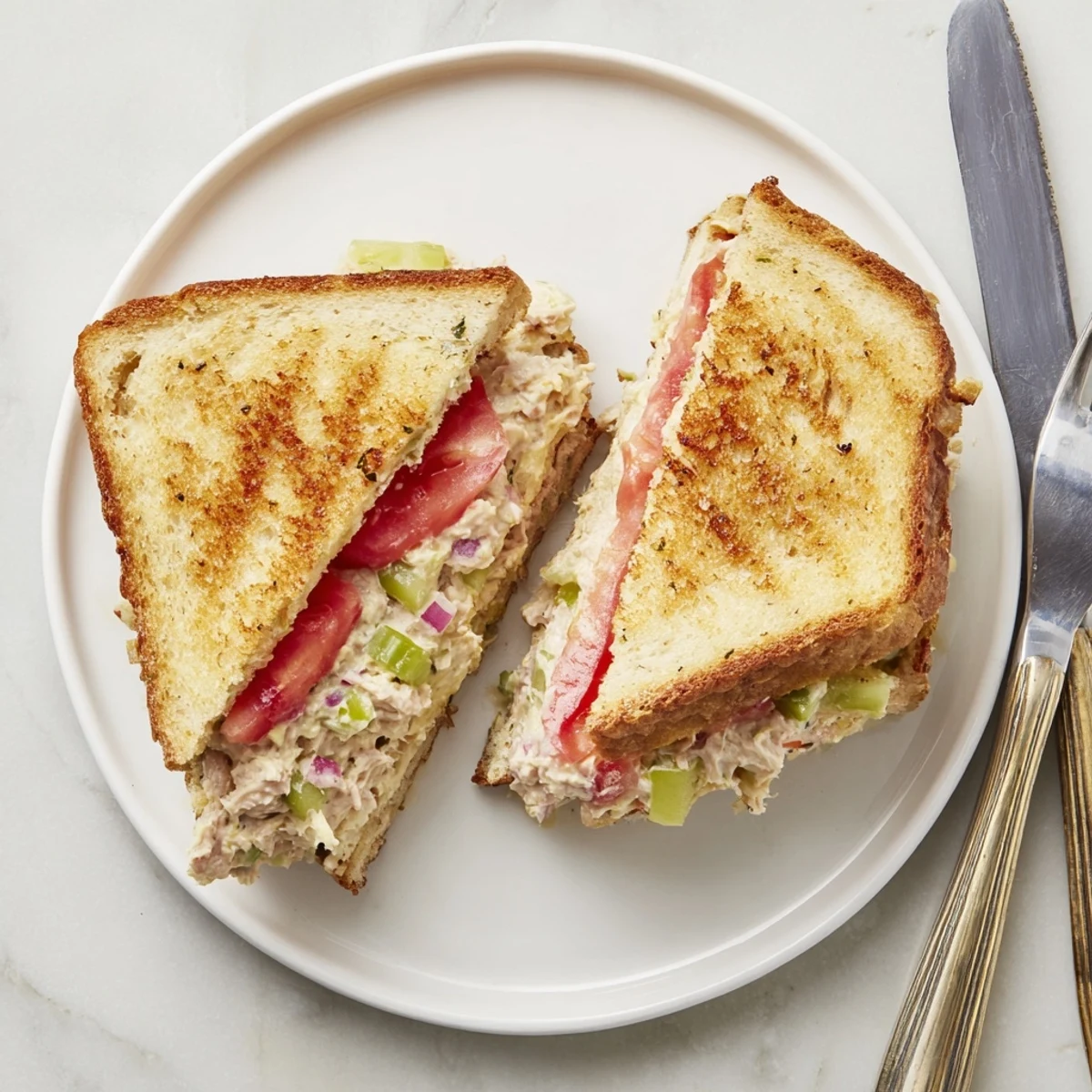Golden grilled tuna melt sandwich oozing melted cheddar over creamy tuna salad on white bread