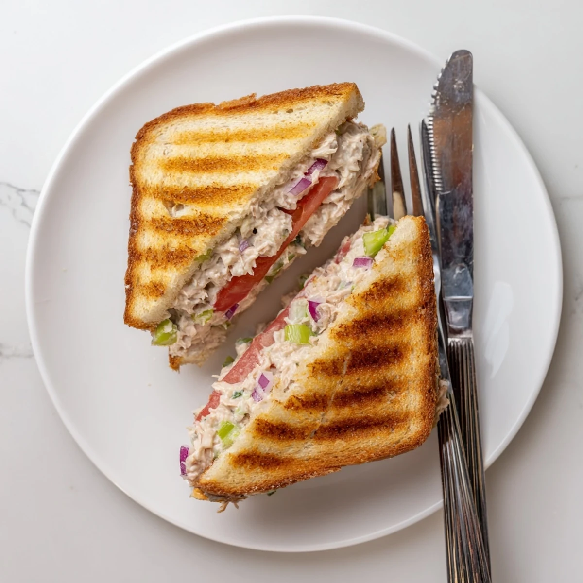 Classic tuna melt with swiss cheese melted on buttery sourdough bread, sliced diagonally on a plate