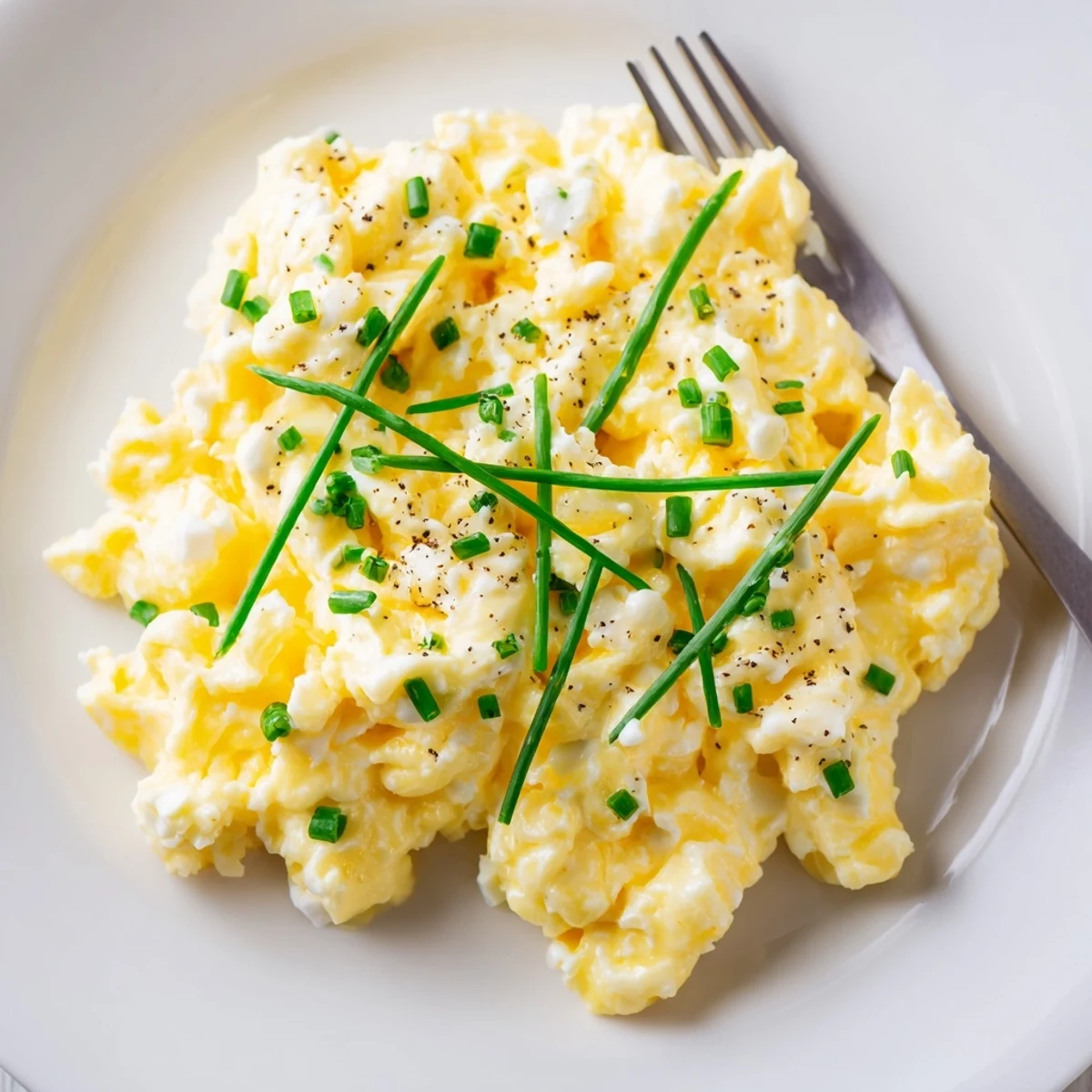 Sunlit plate of Cottage Cheese Scrambled Eggs with Chives, fluffy and creamy.