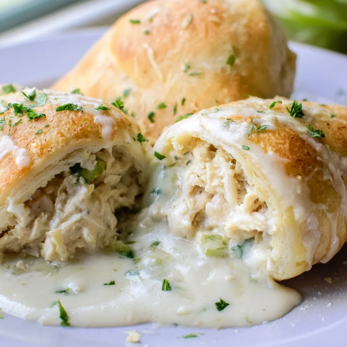 Golden baked chicken pillows wrapped in crescent dough drizzled with rich parmesan sauce