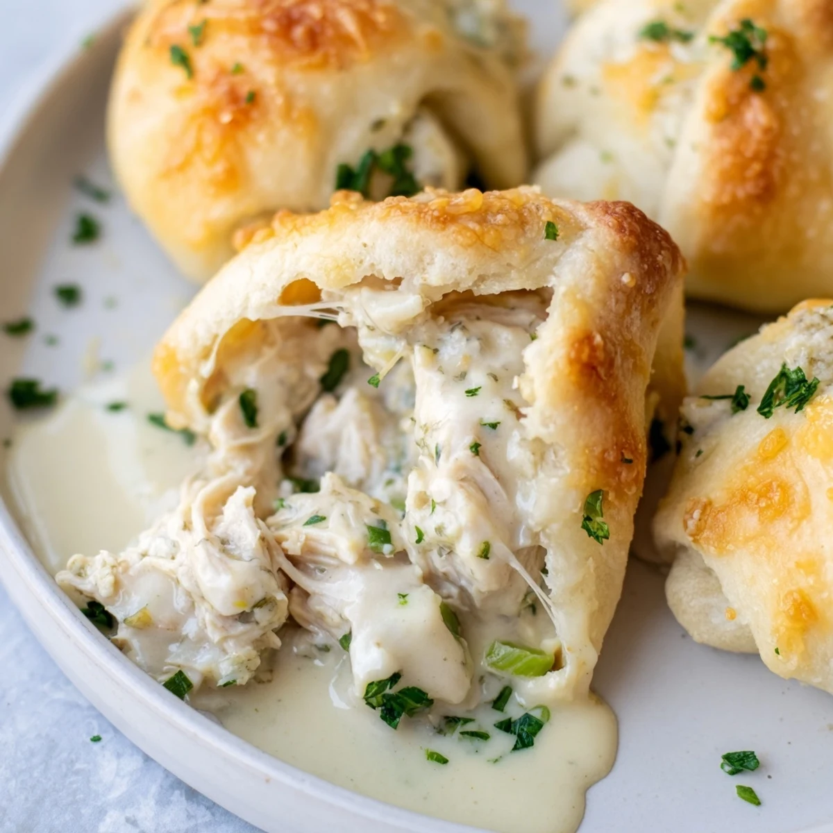 Flaky crescent rolls stuffed with seasoned chicken breast topped with creamy white parmesan sauce