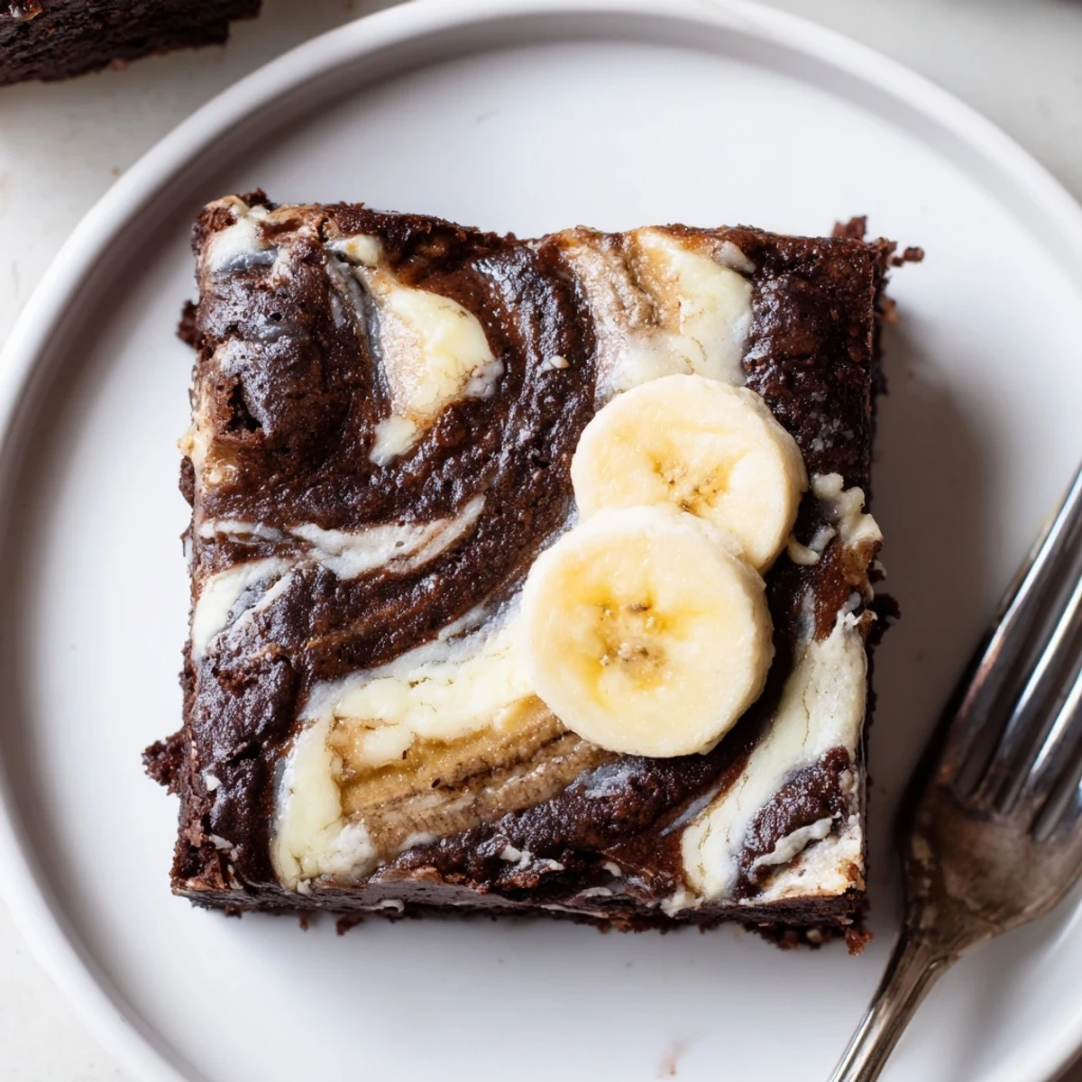 Warm Banana Pudding Brownies cooling in pan, topped with sliced banana