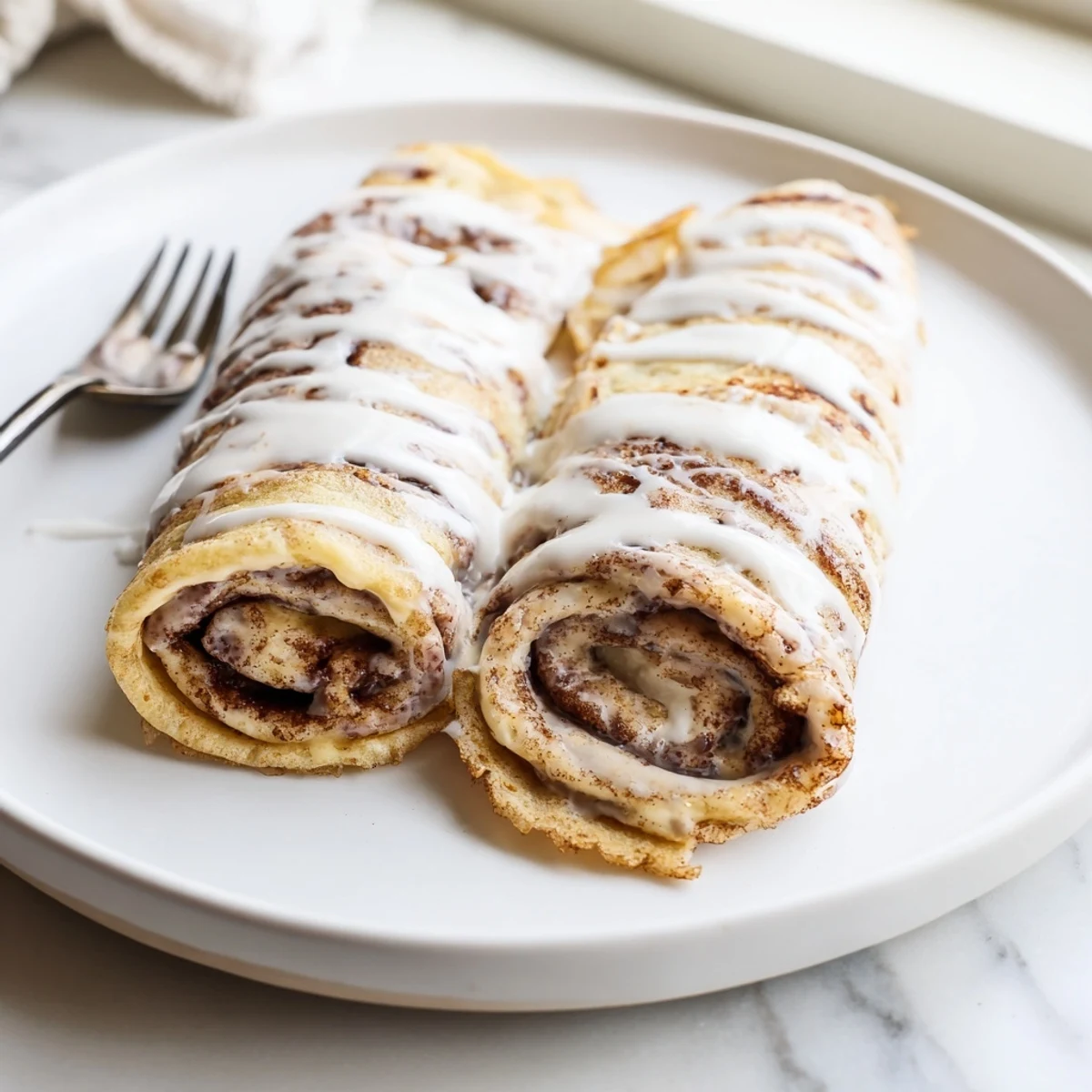 Golden crepes filled with creamy cinnamon swirl filling topped with powdered sugar glaze