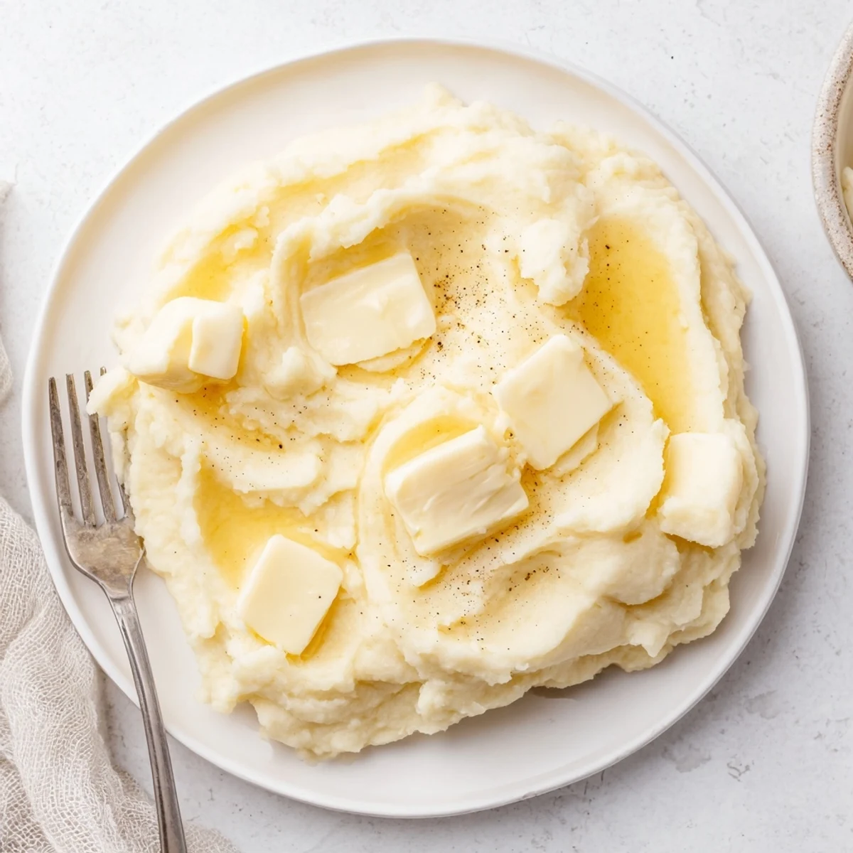 Velvety Mashed Potatoes swirled with melted butter in a warm ceramic bowl