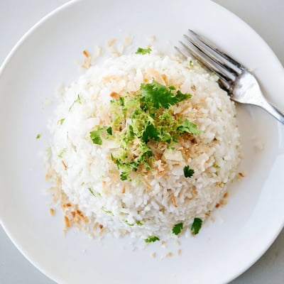 Steaming bowl of fragrant coconut rice topped with fresh cilantro and lime zest
